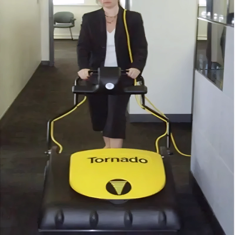 Operator pushing the Tornado CK 3030 wide-area vacuum across a carpeted floor