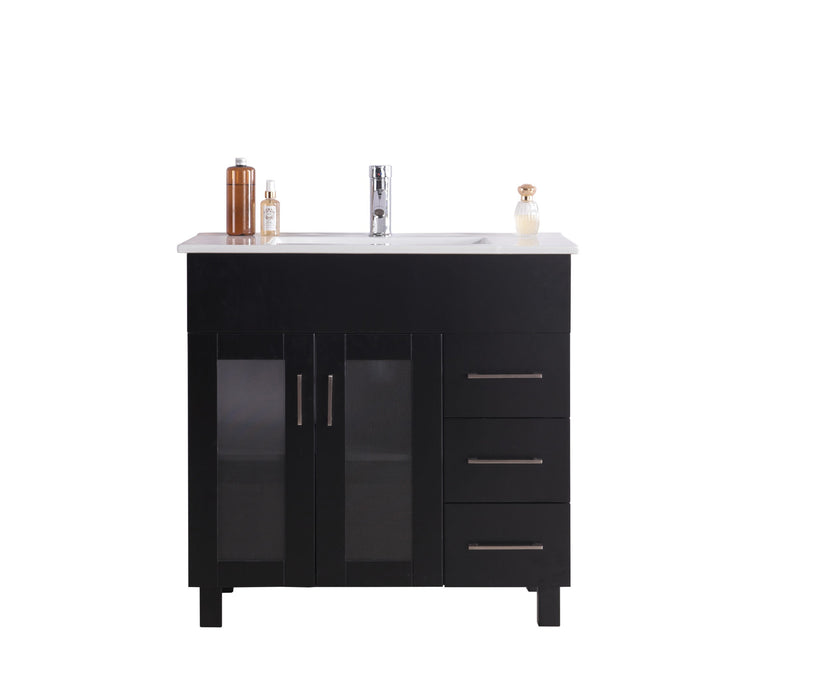 Bathroom vanity with white countertop, black cabinet, three drawers, and two glass-paneled doors.