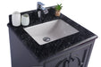 Bathroom vanity with a black granite countertop, white basin, chrome faucet, toothbrush holder, and a small plant in a glass jar.