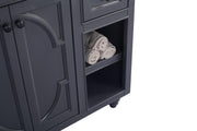 Close-up of a gray vanity with rolled towels in the open shelving.