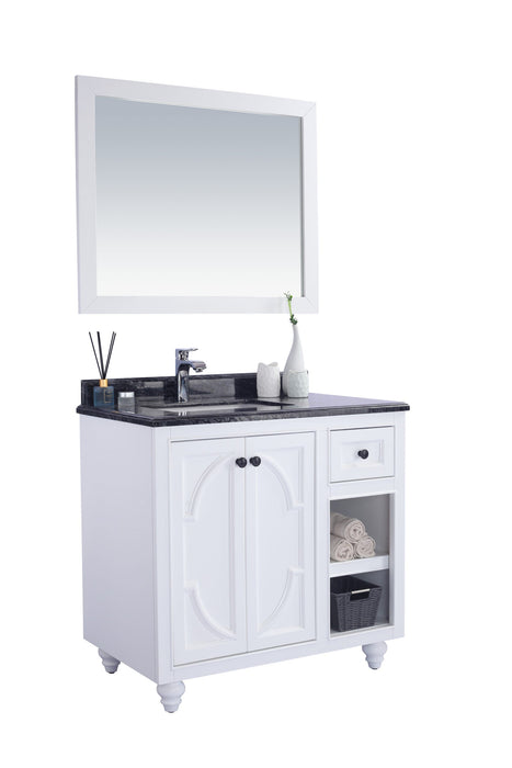 White bathroom vanity with black granite countertop, silver faucet, and white framed mirror.