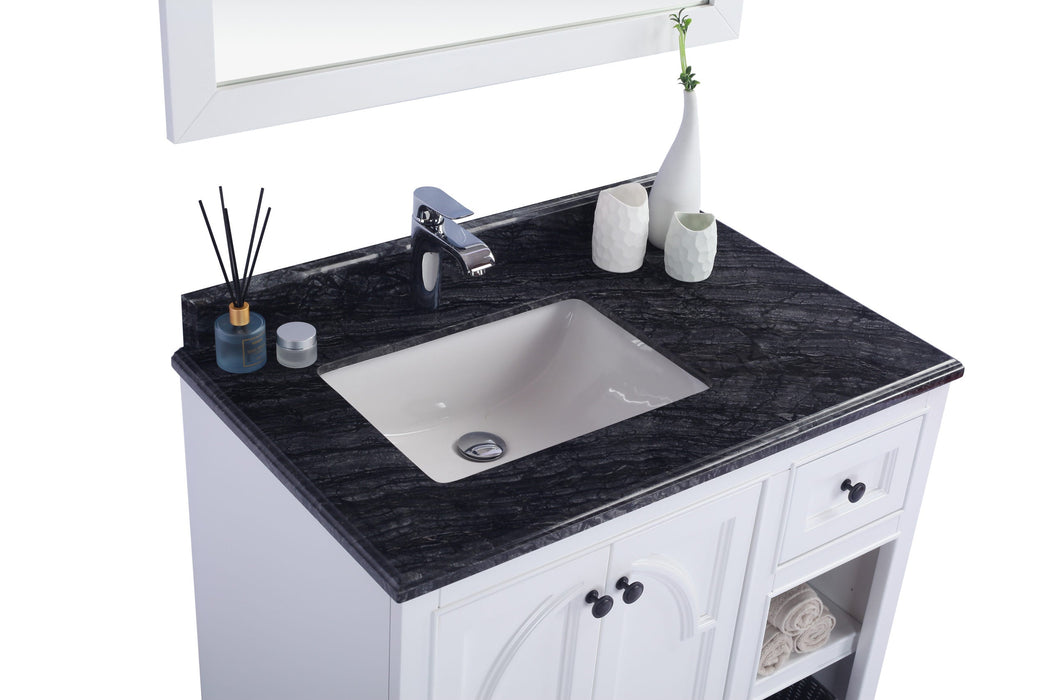 Bathroom vanity with a black countertop, white cabinet, and white sink.