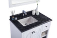 Bathroom vanity with a black countertop, white cabinet, and white sink.