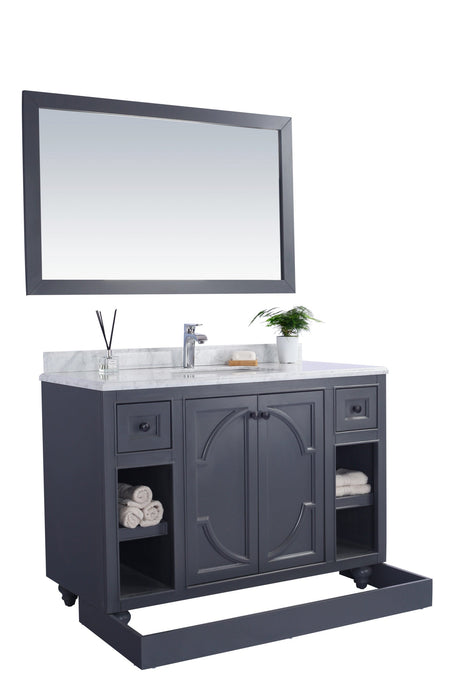Gray vanity with marble top, mirror, and decorative items.
