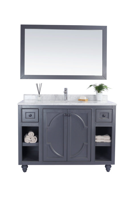 Gray bathroom vanity with mirror, marble countertop, and rolled towels.