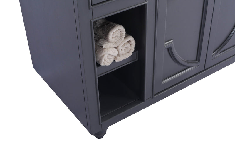 Gray vanity with rolled towels in shelf.
