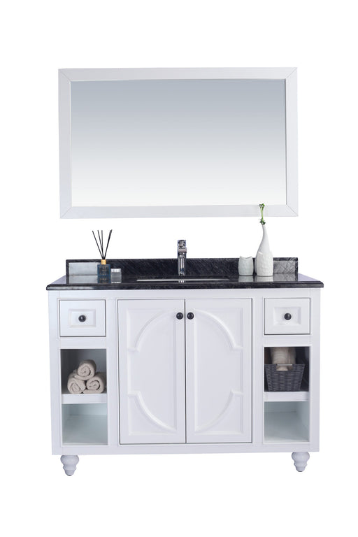 White bathroom vanity with black granite countertop and mirror.