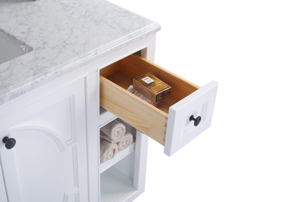 Bathroom vanity with marble top, open drawer, and rolled towels.
