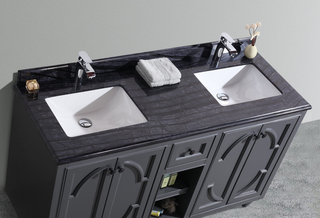 Double-sink vanity with gray cabinet, dark marble top, chrome faucets, towels, and bathroom accessories.