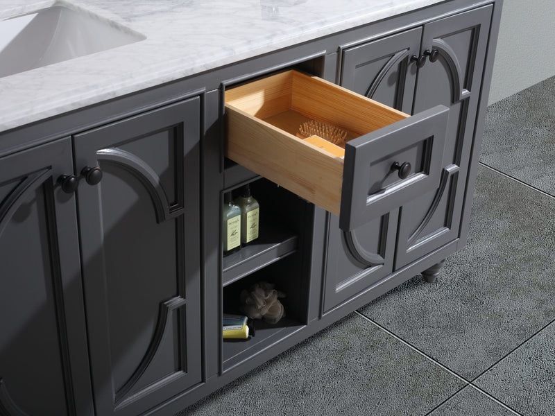 Gray bathroom vanity with marble top, opened drawer, and open shelf.