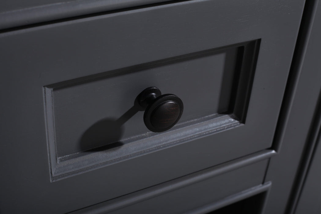 Close-up of a gray wooden drawer with a black round knob, creating a shadow on the drawer's surface.