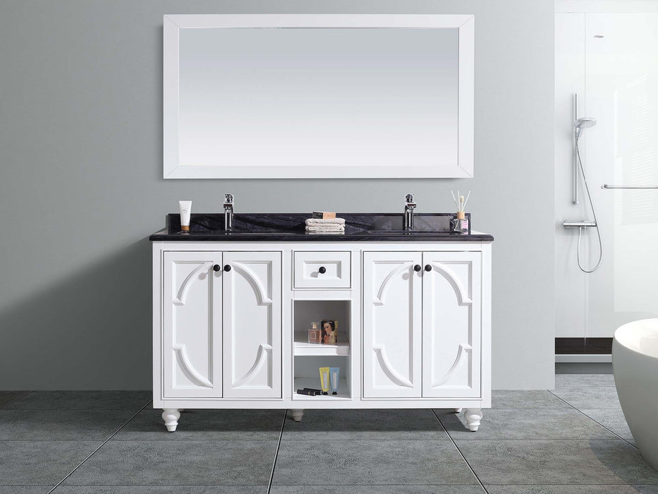 White bathroom vanity with black countertop and white framed mirror.