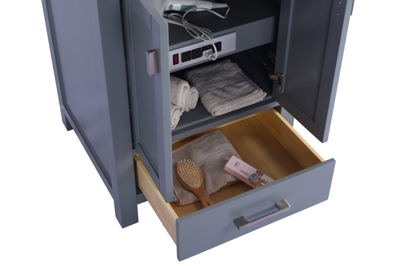 A grey vanity cabinet with an open door and extended drawer.  Inside are towels, a brush, and toiletries.