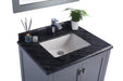 Gray vanity with black marble countertop and white sink.