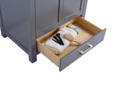 Gray vanity with open drawer containing makeup brushes, a hairbrush, and a white towel.