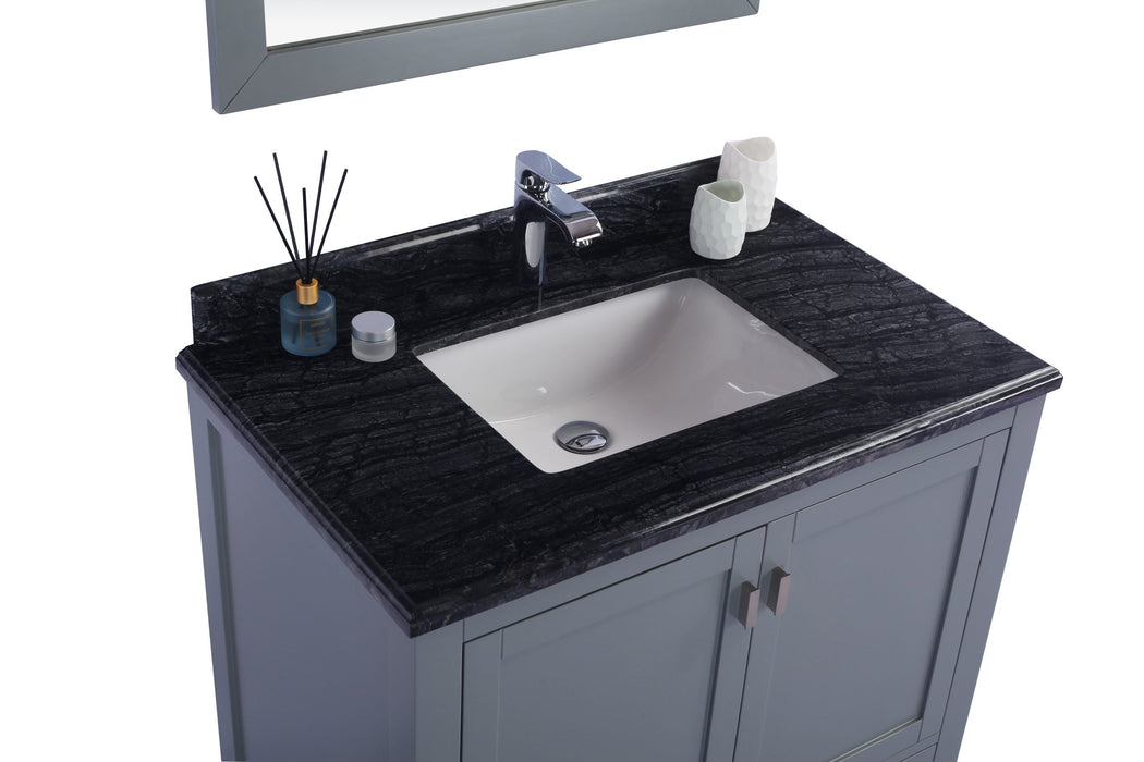 Bathroom vanity with dark countertop, white sink, and gray cabinet. A mirror is partially visible at the top.
