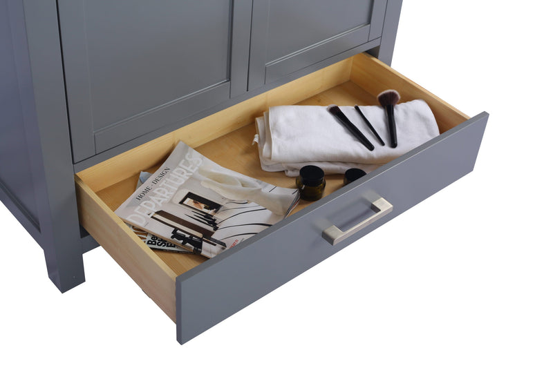 Gray vanity cabinet with an open drawer filled with magazines, a white towel, and cosmetics.