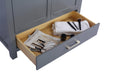 Open grey vanity drawer with wooden interior holding magazine, white towel, makeup brushes, and skincare products.
