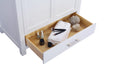 White vanity with an open drawer holding toiletries, brushes, and towels.