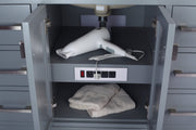 Gray bathroom vanity with a white hair dryer and towels inside an open cabinet door.
