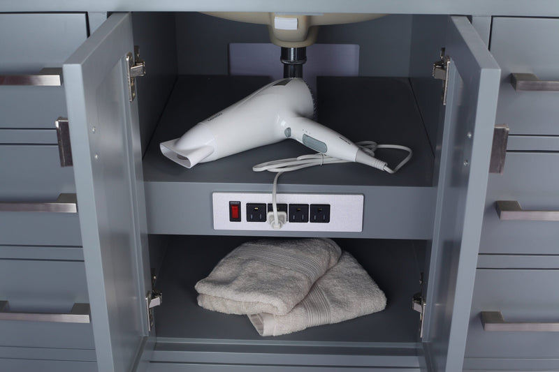 Gray bathroom vanity with a white hair dryer and towels inside an open cabinet door.