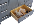 Gray vanity with open drawer containing bath items.