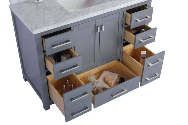 Gray bathroom vanity with marble top and open drawers revealing contents.