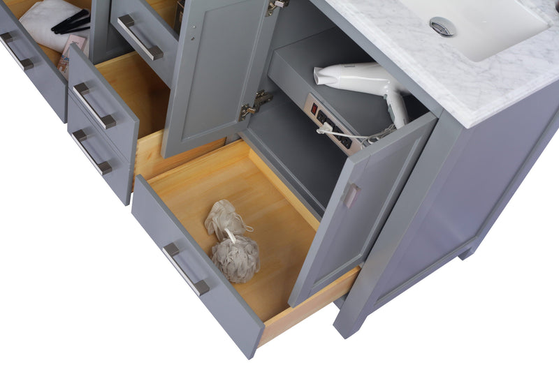 Gray bathroom vanity with open drawers and cabinets, containing a hair dryer, towels, makeup, and bath accessories.