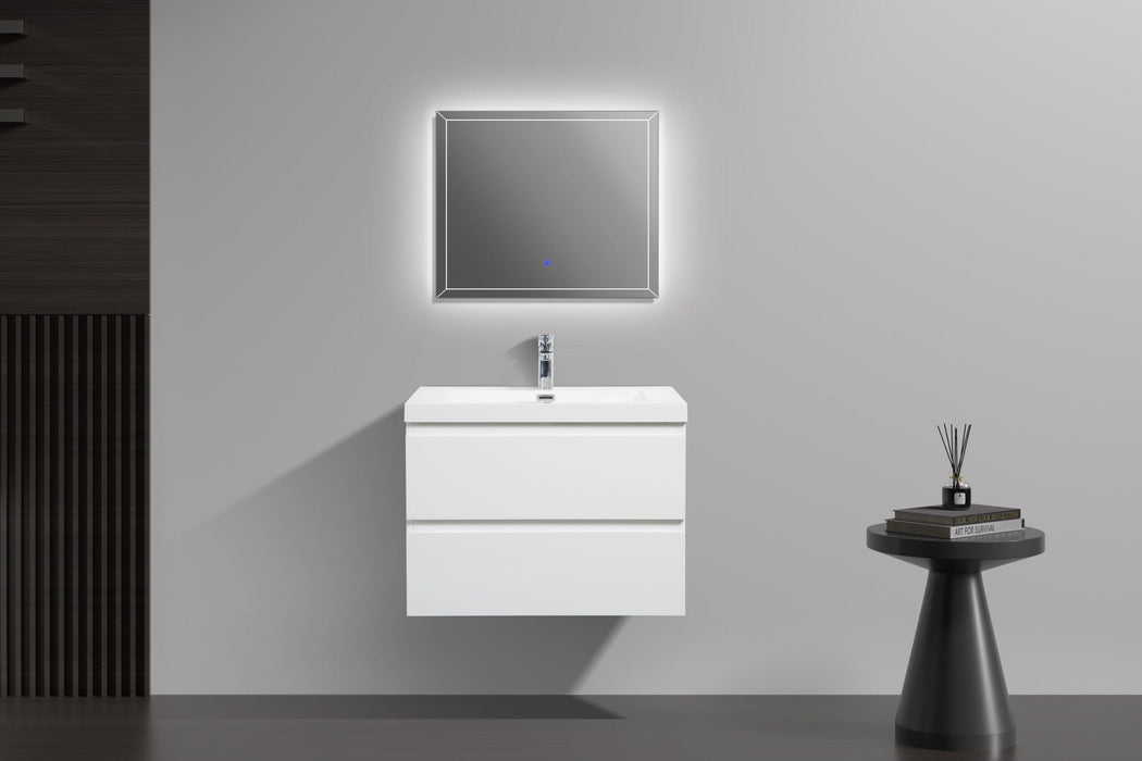 Bathroom interior with a white vanity, illuminated mirror, and a small black side table with books and a diffuser.