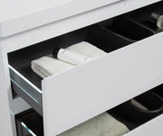 Open white vanity drawer with towel and skincare.