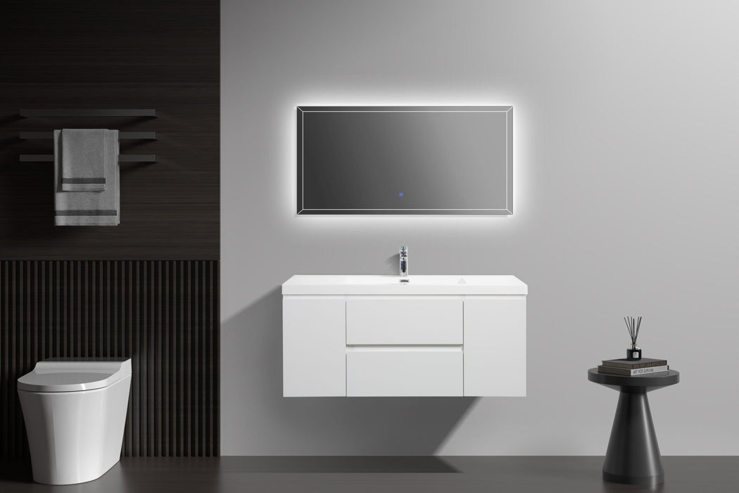 Bathroom with white vanity, illuminated mirror, toilet, and side table.