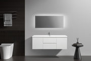 Bathroom with white vanity and toilet, dark wood accent wall, and illuminated mirror.