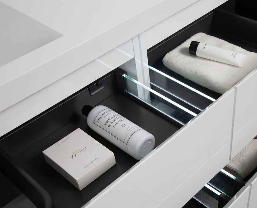 Open bathroom drawer with black interior, white towels and beauty products.