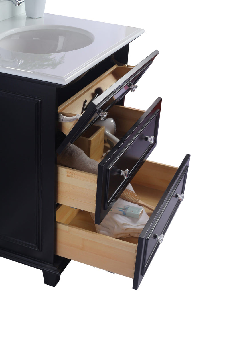 Bathroom vanity with three open drawers. Drawers contain bathroom accessories. Black frame, clear knobs.