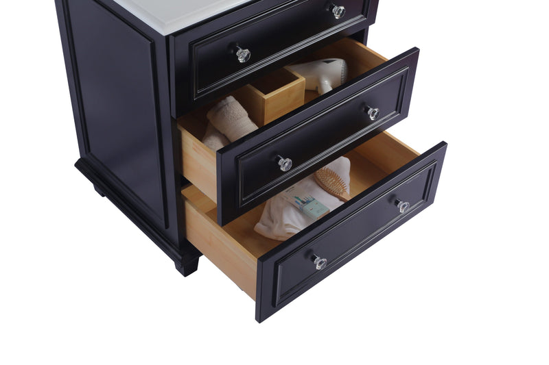 Navy blue vanity with three open drawers, filled with towels, a hair dryer, and other items. The drawers have clear glass knobs.