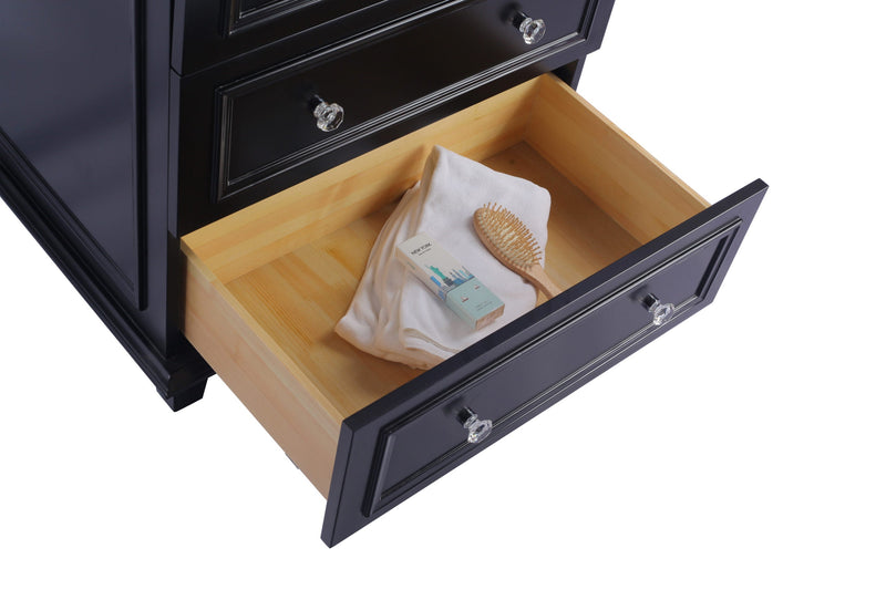 Black dresser with an open drawer revealing a white towel, hairbrush, and a New York themed box.
