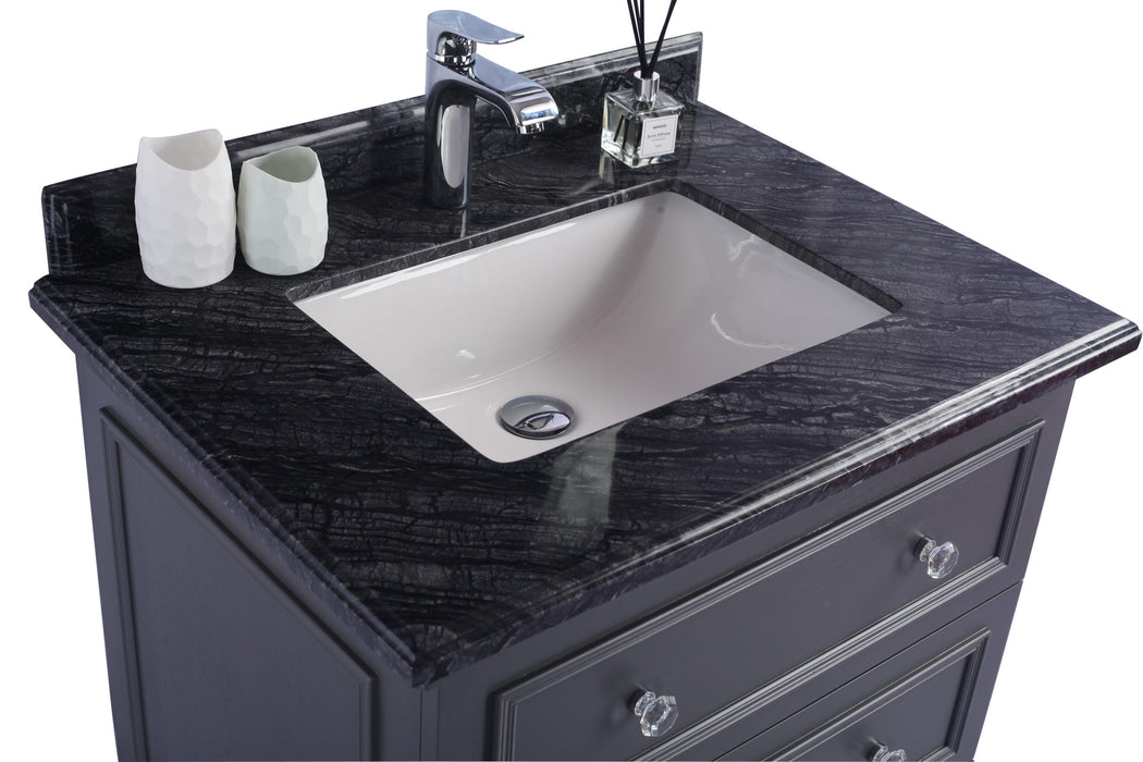 Bathroom vanity with black marble top, white sink, chrome faucet, decorative containers, and crystal drawer pulls.