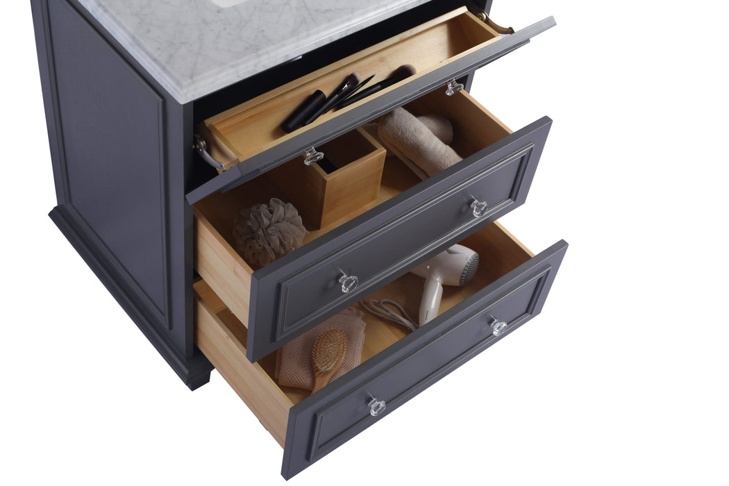 Gray vanity with three open drawers, each with a clear knob, filled with toiletries and grooming items.