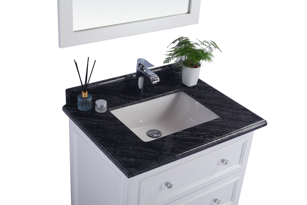 Bathroom vanity with black granite countertop and white cabinetry.