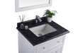 Bathroom vanity with black granite countertop and white cabinetry.