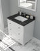 White vanity with black countertop, drawers, sink, and bathroom accessories.