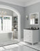 Elegant bathroom with white vanity, marble floor, arched doorway, and chandelier.
