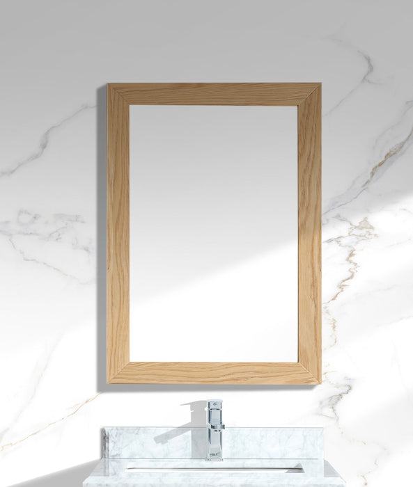 Bathroom mirror with light wood frame on marble wall above marble sink.
