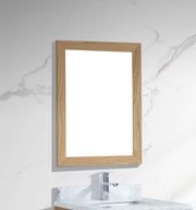 Wooden-framed mirror on marble wall above sink and faucet. 
