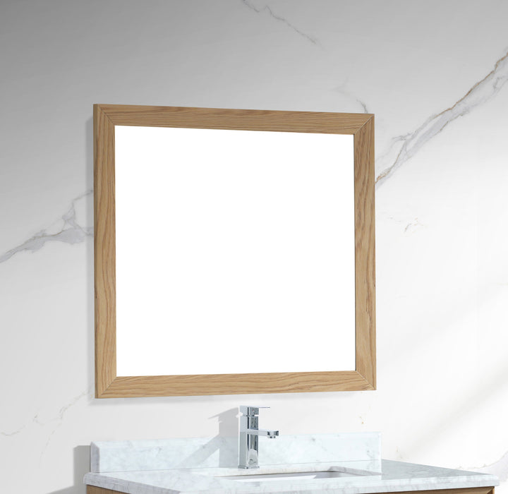 Square, wood-framed mirror above a bathroom vanity with marble countertop and chrome faucet.