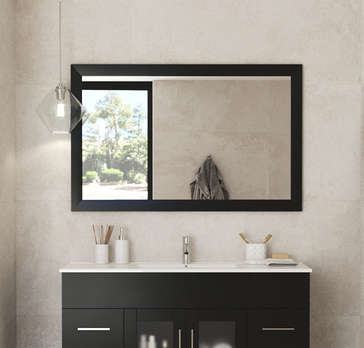 Bathroom vanity with a black cabinet, white countertop, and a black-framed mirror with a window.
