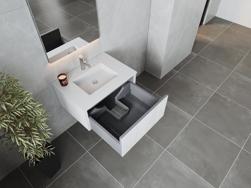 Bathroom vanity with open drawer, plant, candle, tiled floor and walls.
