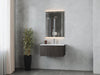 Bathroom with gray marble walls, floating dark-wood vanity, lighted mirror, and potted plant.
