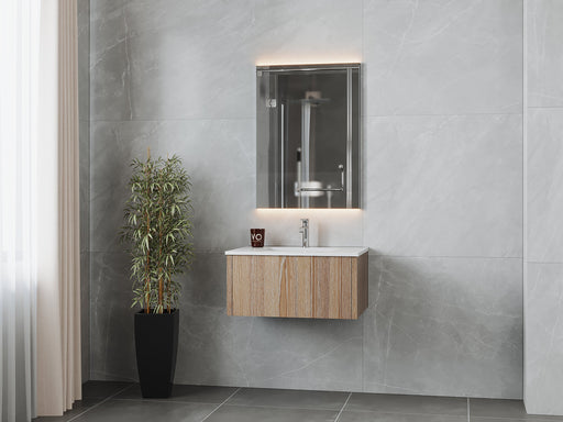 Modern bathroom vanity with wooden cabinet, white countertop, illuminated mirror, potted plant, and gray tile walls.
