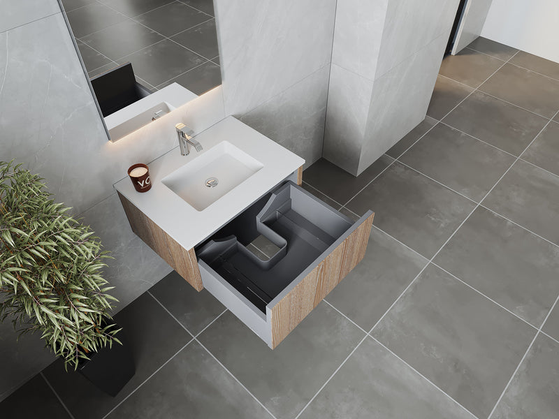 Bathroom sink with open drawer, candle, and plant.